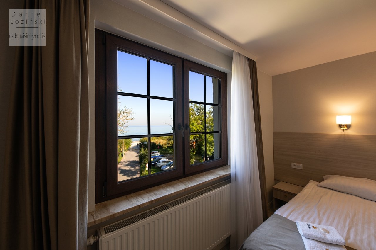 Fasteignamynd. Mynd af hótelherbergi með nærmynd af sjávarútsýni úr glugganum. Ljósmyndun fyrir fyrirtæki og hótel. Mynd af innra rými tekin af ljósmyndaranum Daniel Łoziński. Eignasafn - odruvisimynd.is