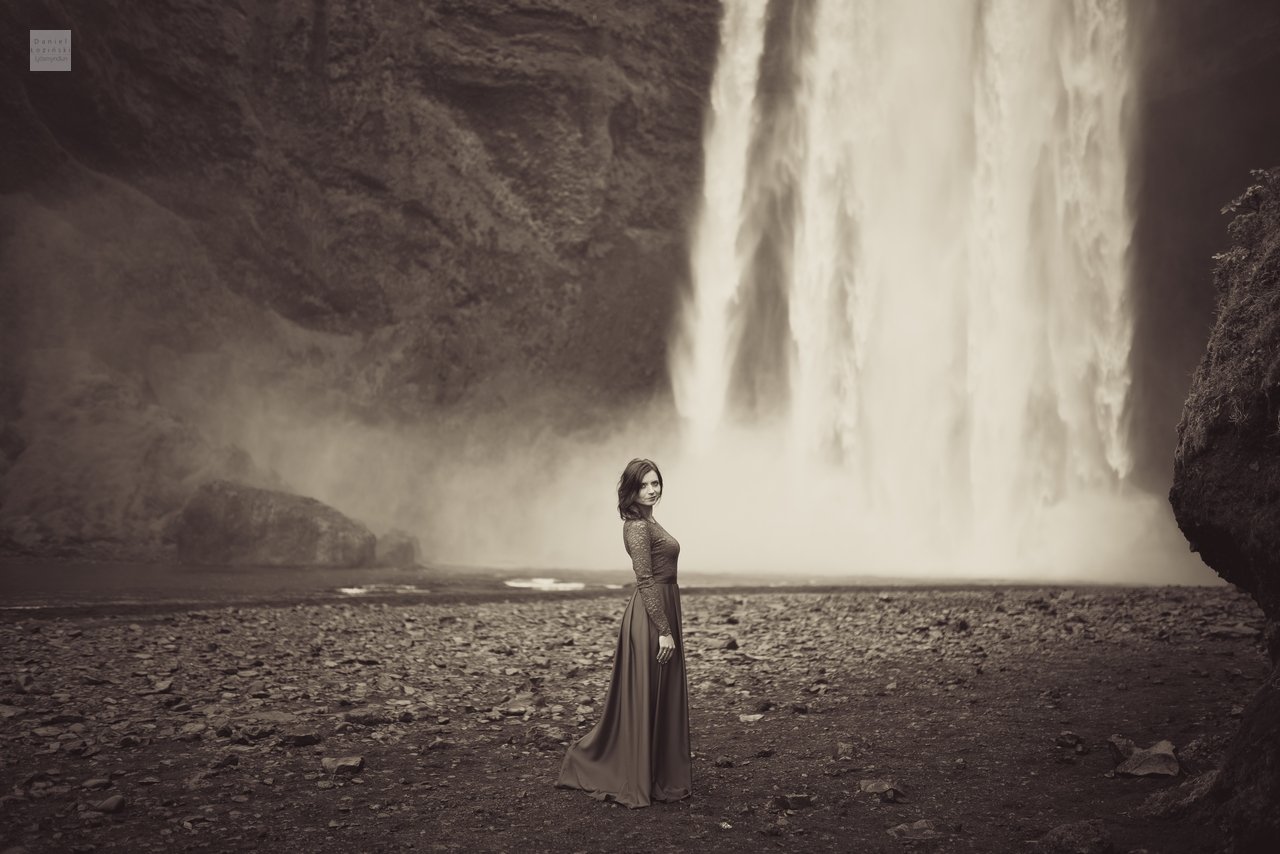 Myndataka af konu í rauðum kjól við fossinn Skógafoss á Íslandi (Golden Circle). Svarthvítar myndir. Ljósmynd tekin af ljósmyndaranum Daniel Łoziński með Nikon D850 myndavélinni og Sigma linsum, ART röð.