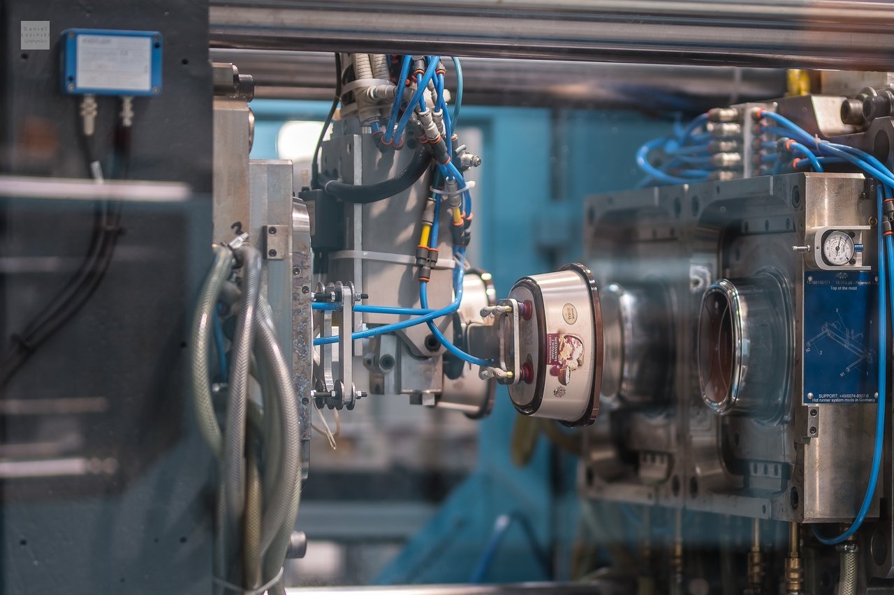 Ljósmynd á framleiðslusalnum í umbúðafyrirtæki. Mynd ljósmynd af verksmiðjunni. Ljósmynd af framleiðsluvélum. Mynd tekin af ljósmyndaranum Daniel Łoziński.