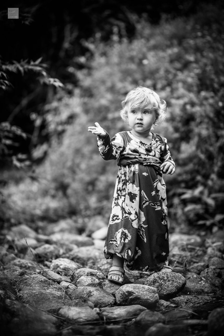 Svarthvít ljósmynd af lítilli stúlku í garðinum. Fjölskyldumynd. Mynd tekin af Daniel Łoziński með Nikon myndavél og Sigma ART linsum.
